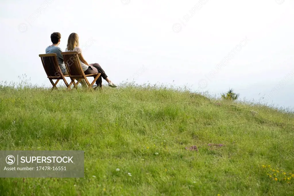 Couple sitting on chairs on top of hill looking at view