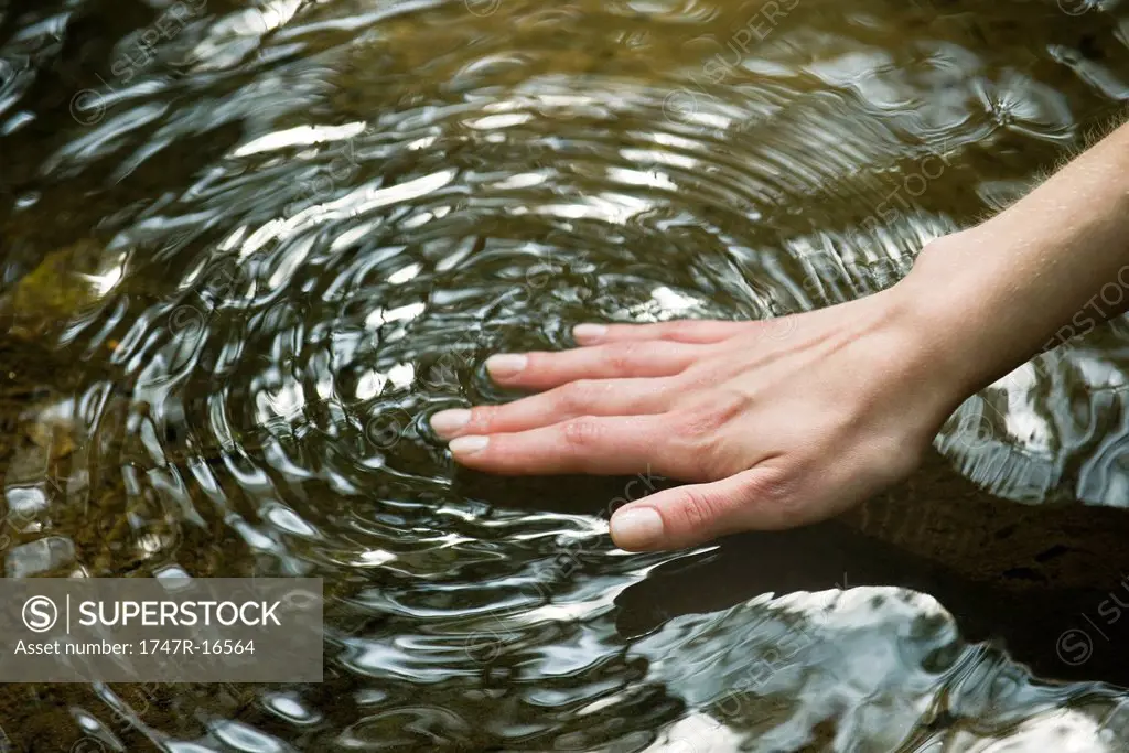 Woman´s hand touching surface of water
