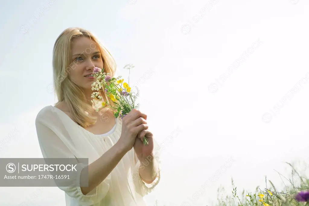 Young woman smelling bouquet of wildflowers