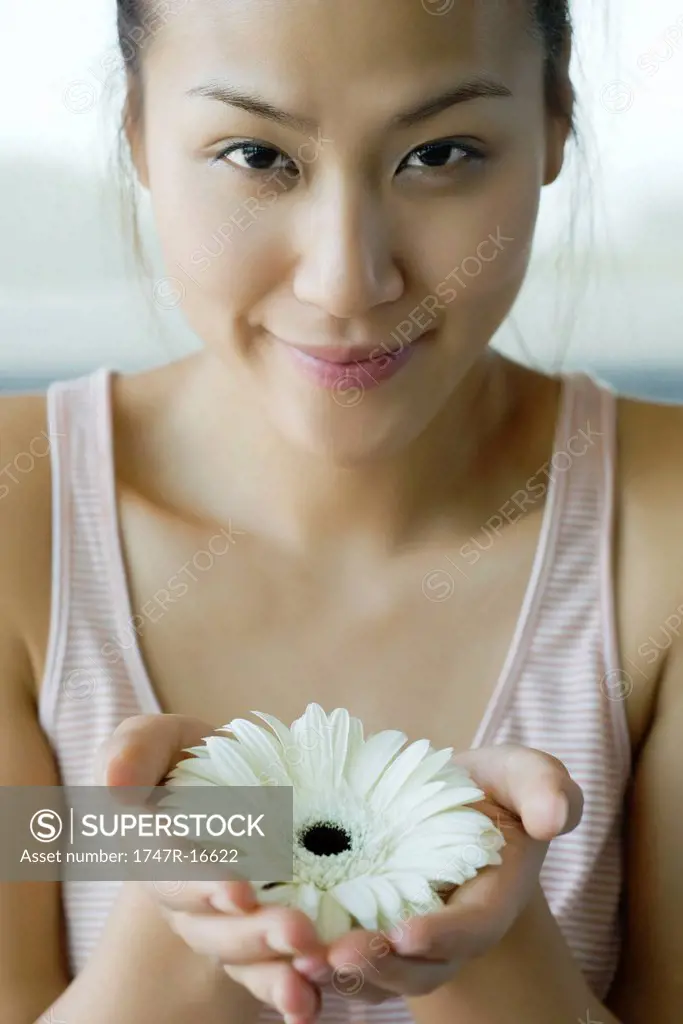 Young woman holding gerbera daisy, portrait