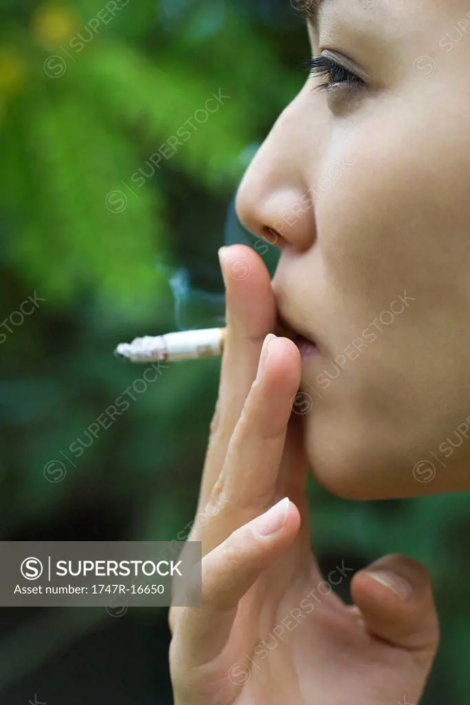Young woman smoking outdoors, side view