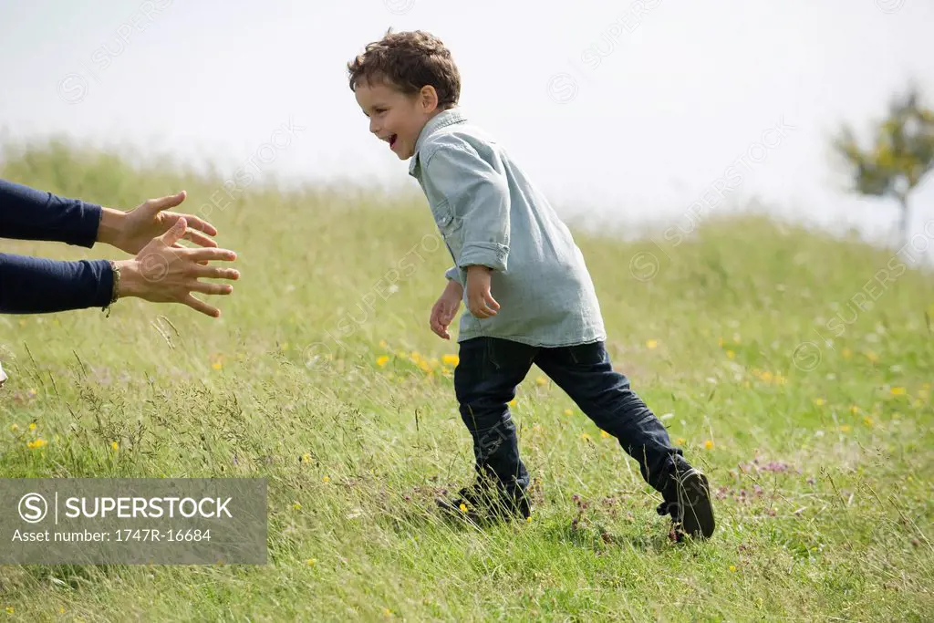 Little boy running toward adult´s arms