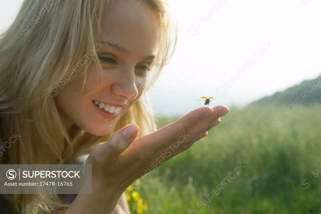 Young woman holding ladybug as it takes off in flight