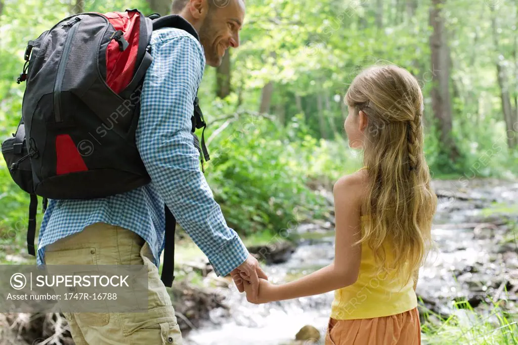 Father and young daughter hiking together in woods