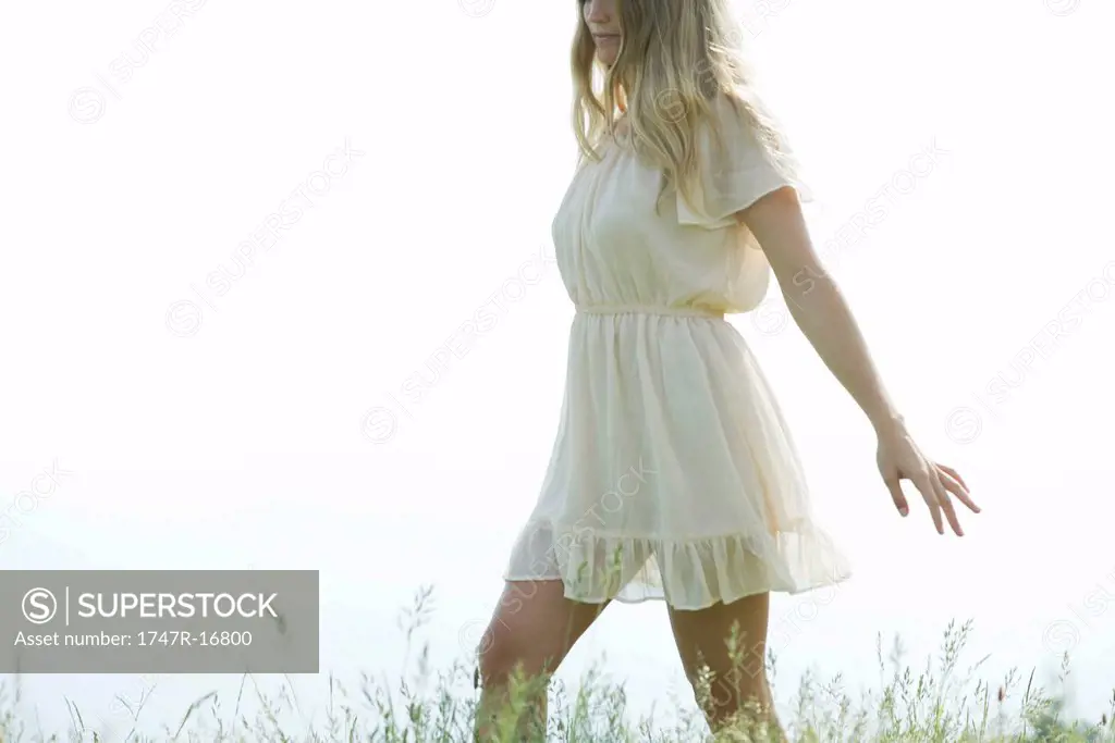 Young woman walking through tall grass