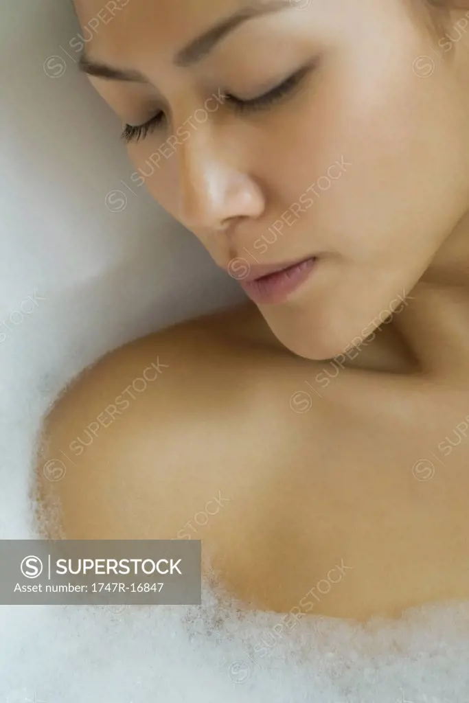 Young woman taking bubble bath, cropped