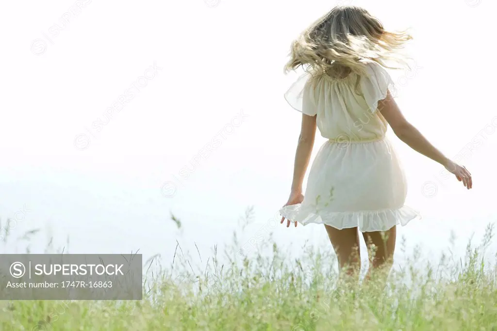 Young woman jumping in meadow, rear view