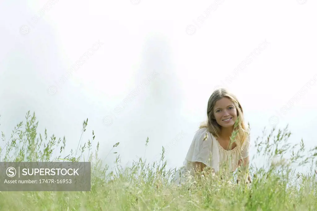 Young woman sitting in tall grass, portrait