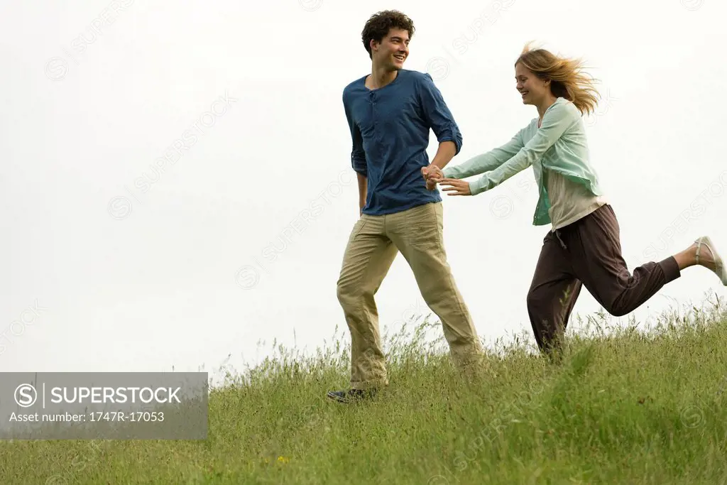 Couple holding hands running on meadow