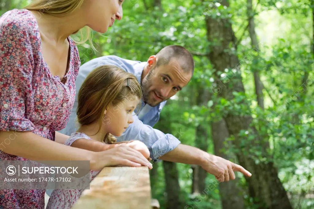 Family outdoors together, looking over railing