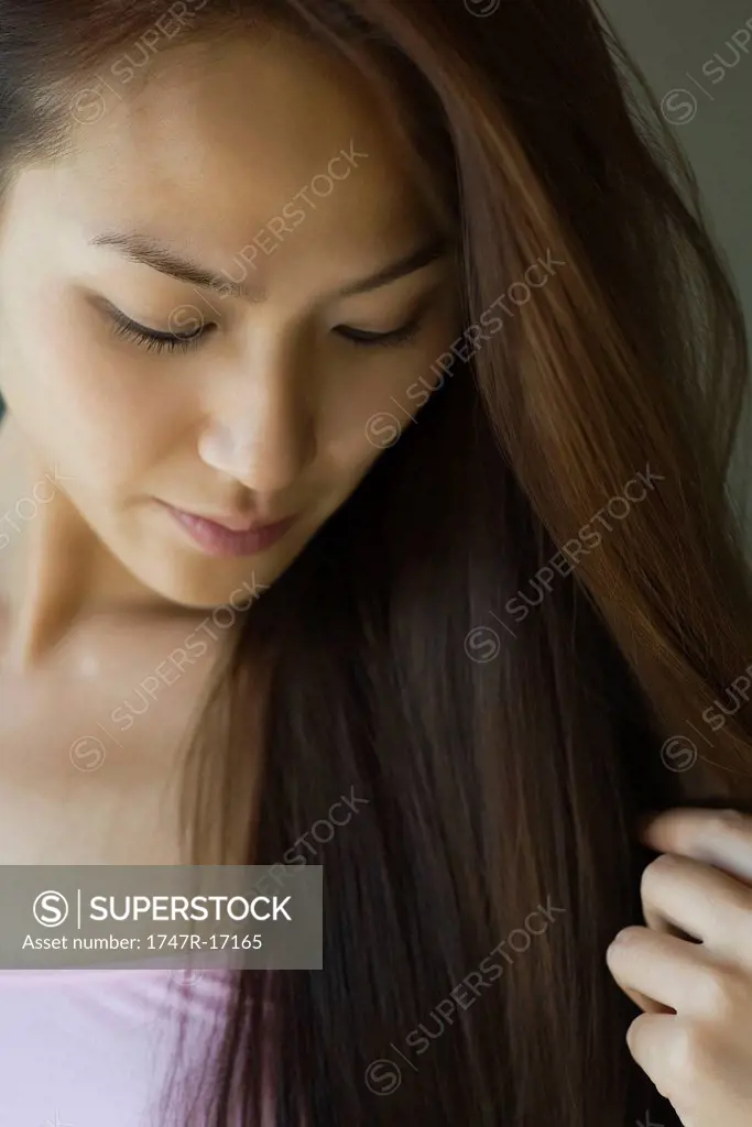Young woman looking down and touching hair