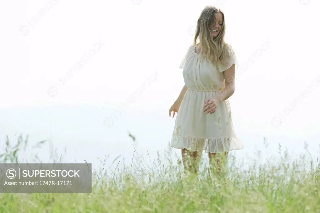 Young woman walking in field of tall grass