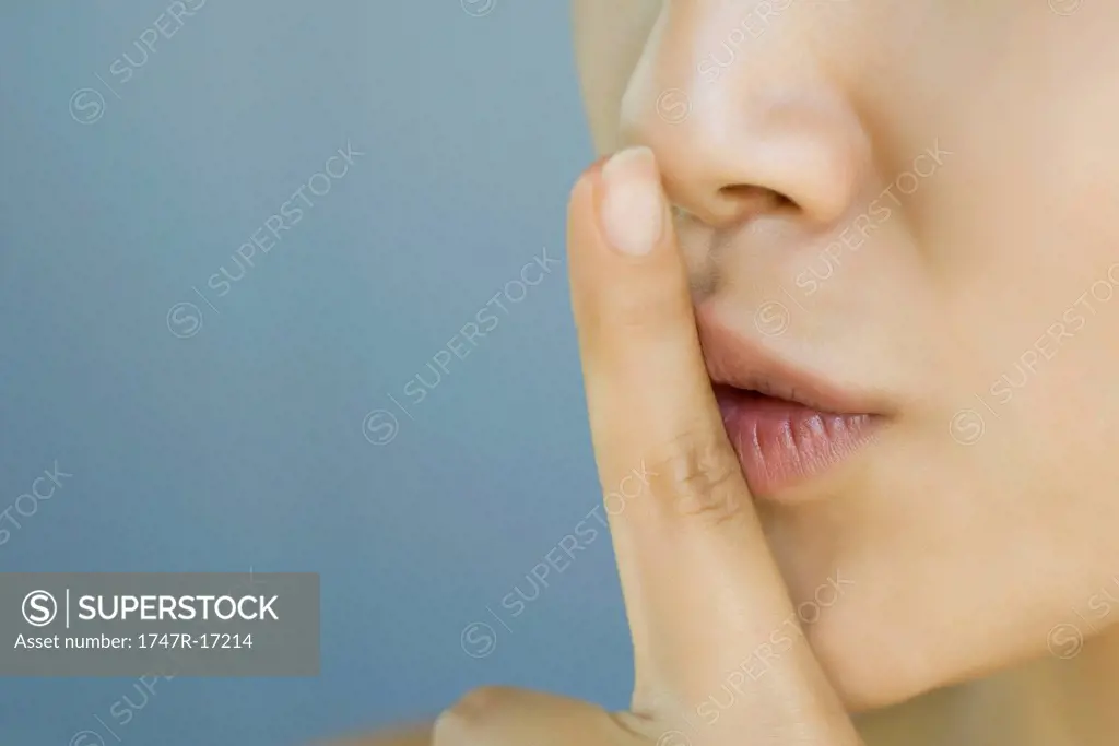 Young woman with finger held to lips, cropped