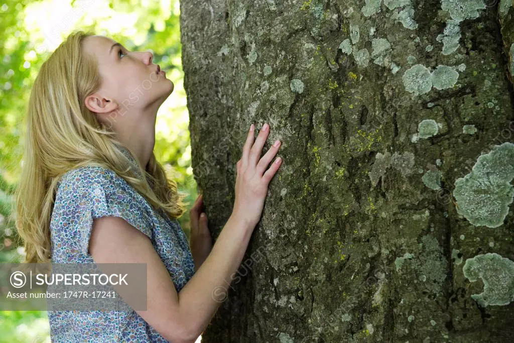Young woman looking up at tree