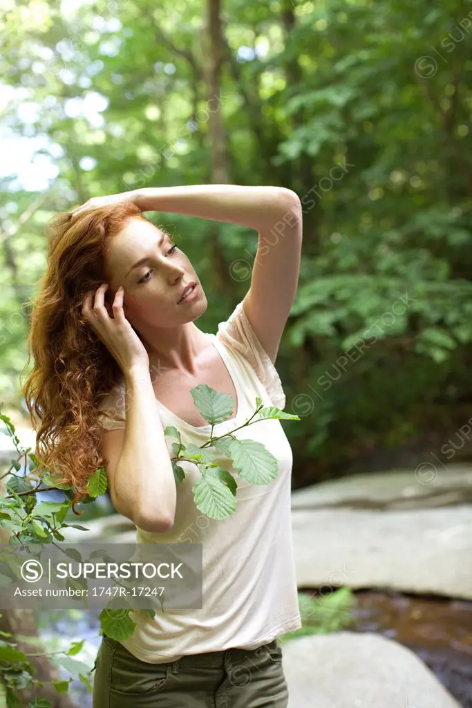 Woman relaxing beside stream with hands in hair