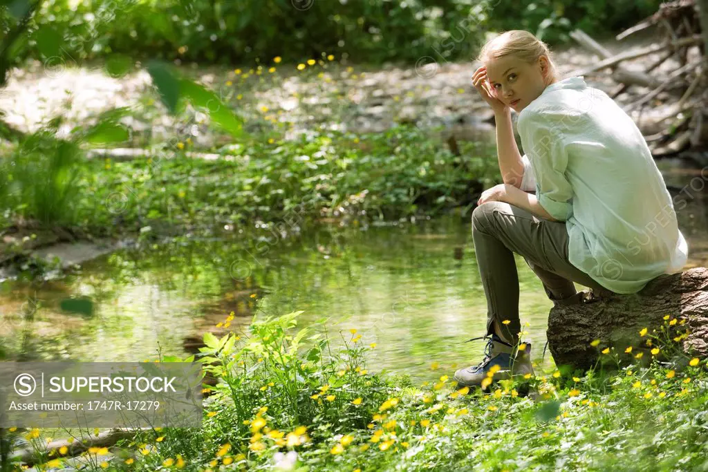 Young woman sitting by river
