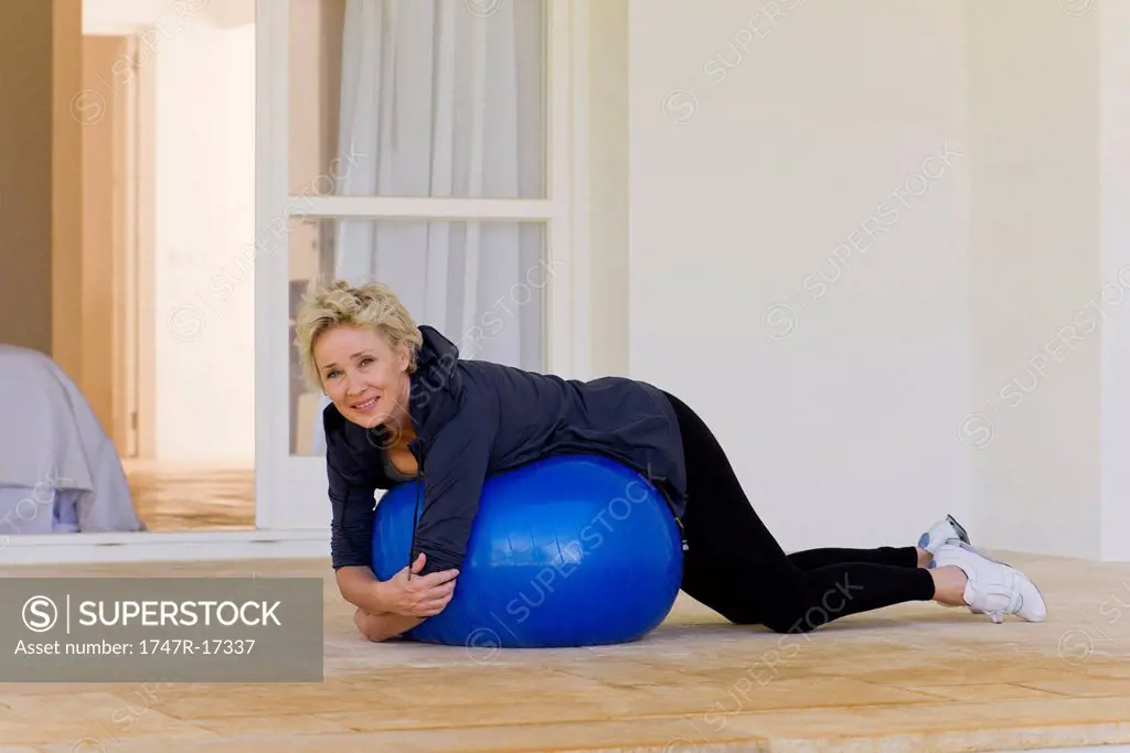 Mature woman lying on stomach on fitness ball