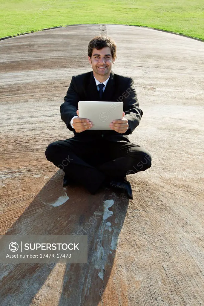 Smiling young businessman with digital tablet outdoors