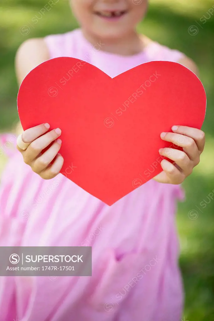 Girl holding paper heart, cropped