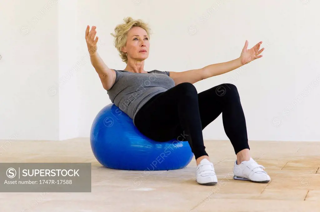 Mature woman doing pilates exercise on fitness ball
