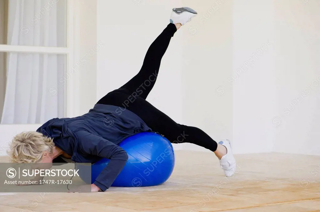 Mature woman doing pilates exercise on fitness ball
