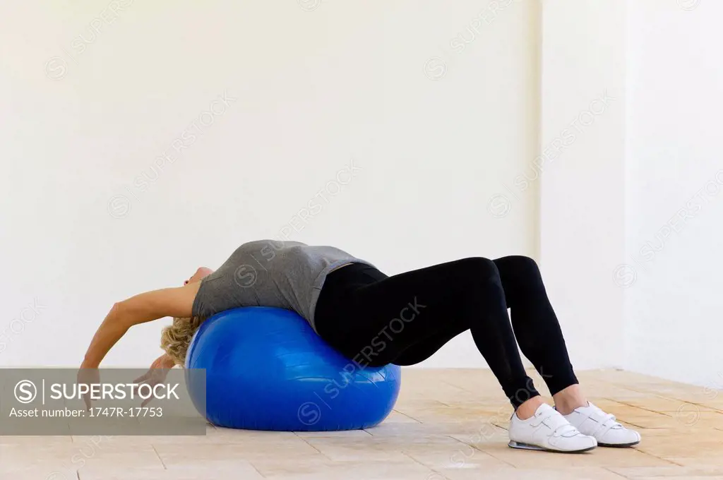 Woman lying on fitness ball stretching