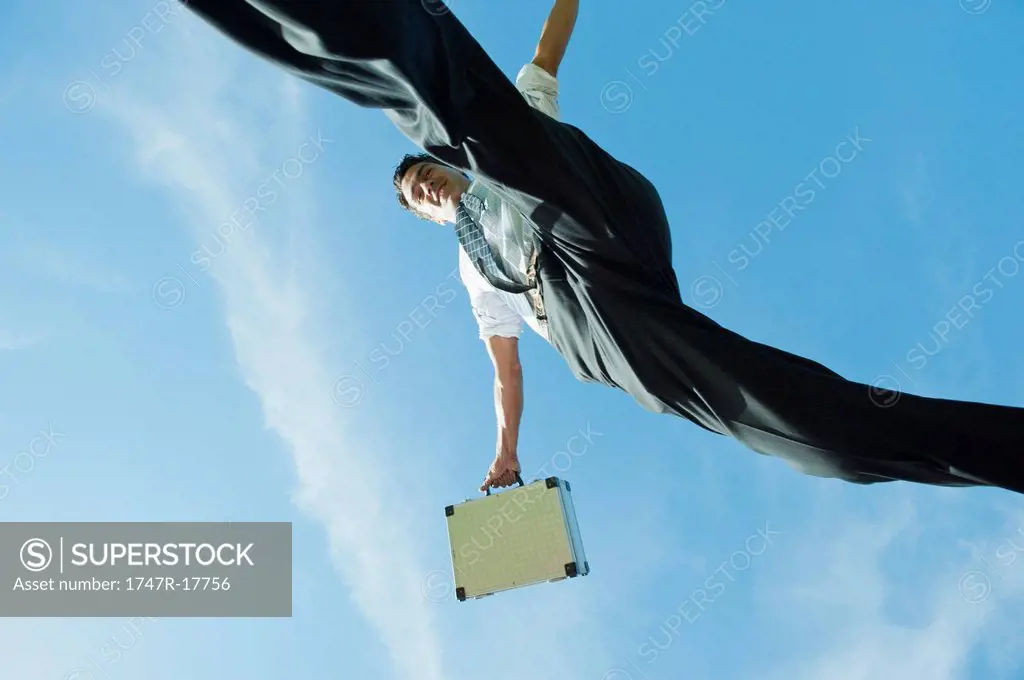 Businessman jumping in air carrying briefcase, directly below