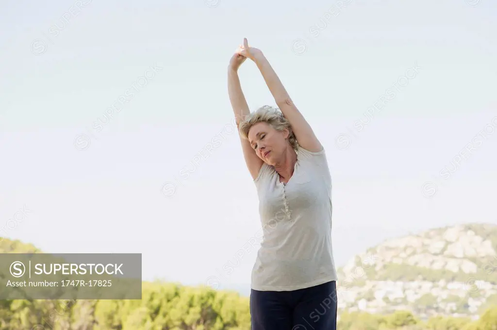 Mature woman stretching arms