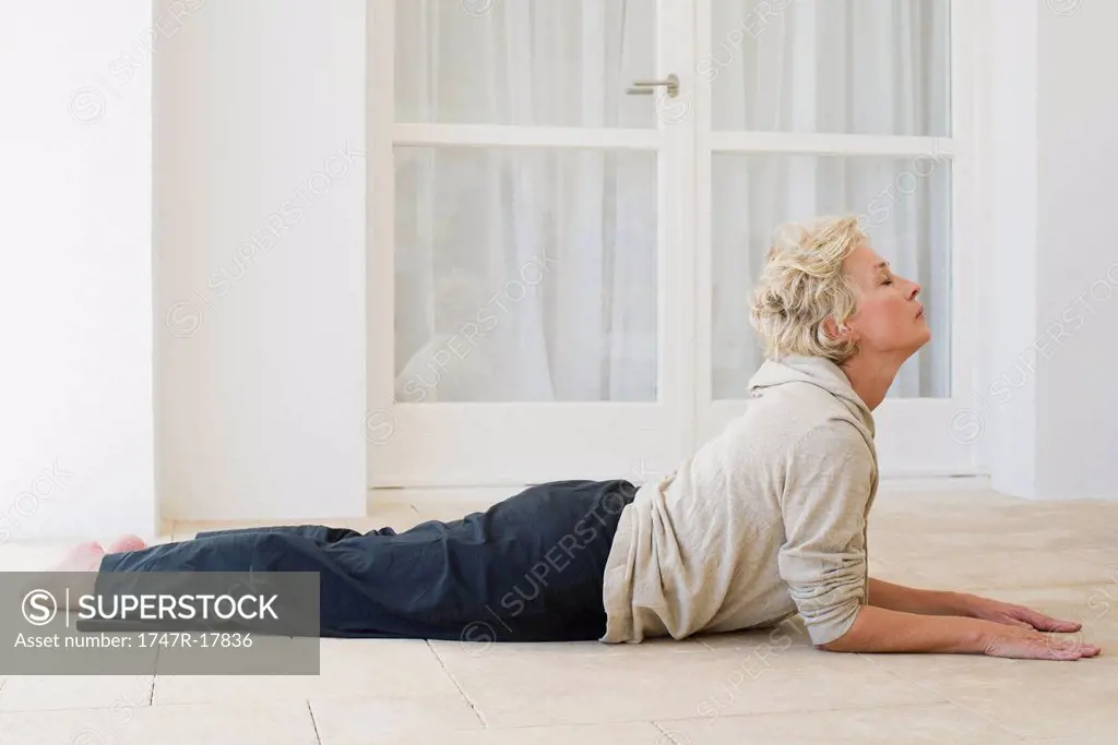 Mature woman doing cobra pose with eyes closed