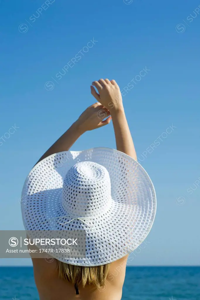 Woman wearing sun hat at the beach, rear view