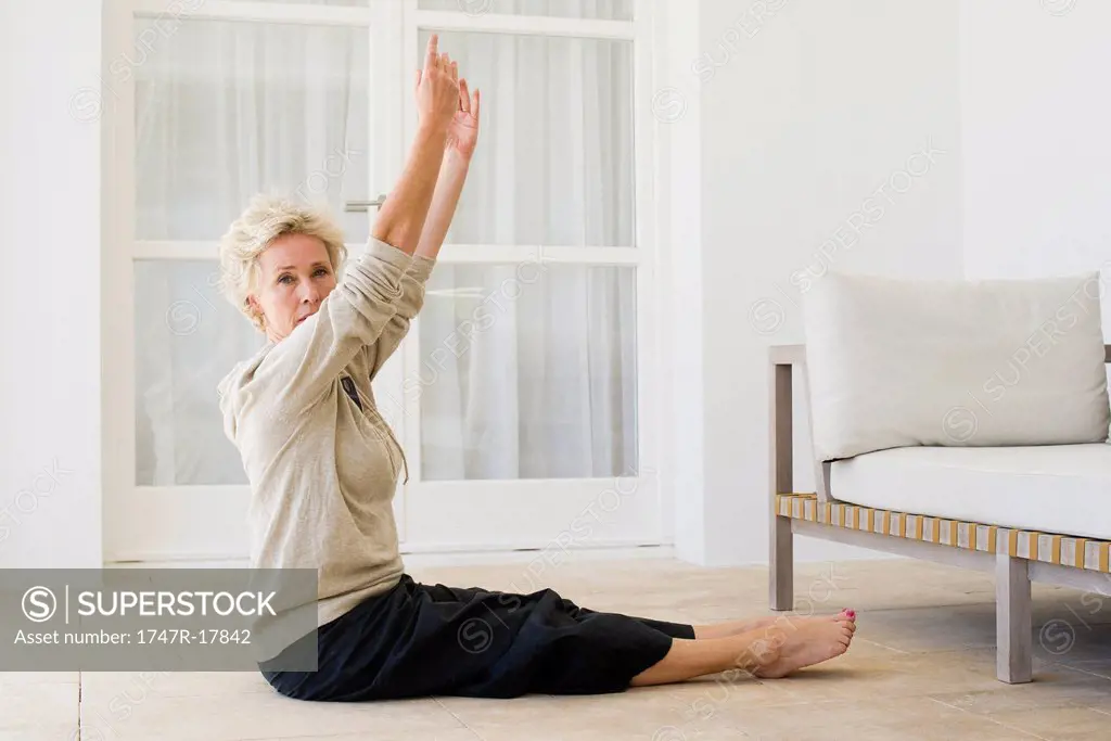 Mature woman practicing yoga on floor