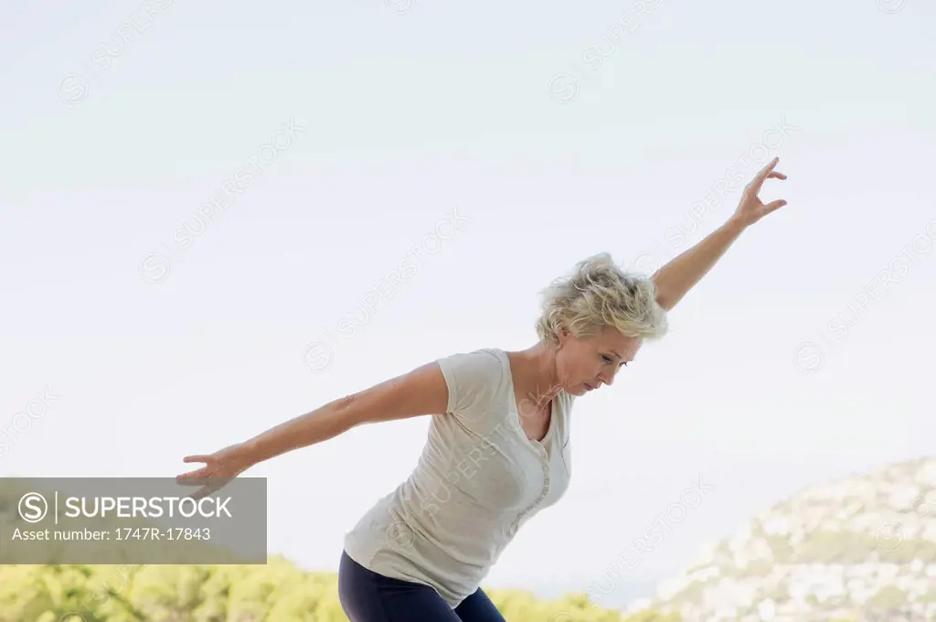 Mature woman exercising with arms outstretched