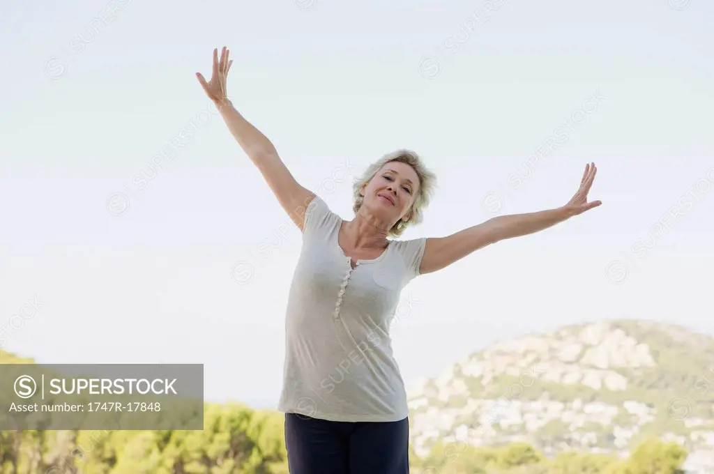 Mature woman exercising with arms outstretched