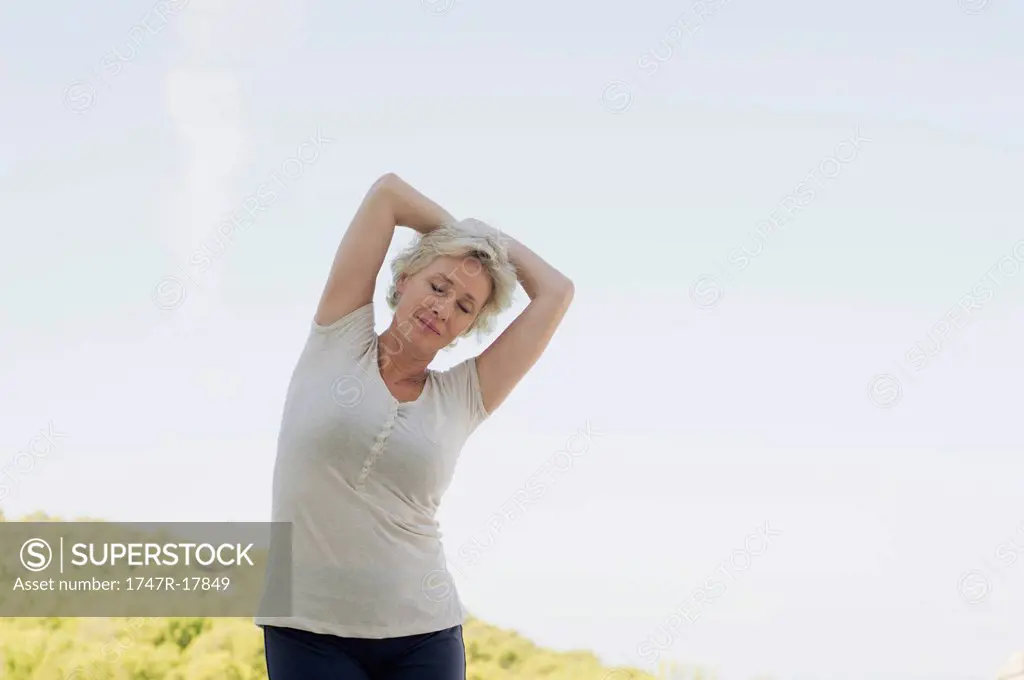 Mature woman stretching with eyes closed