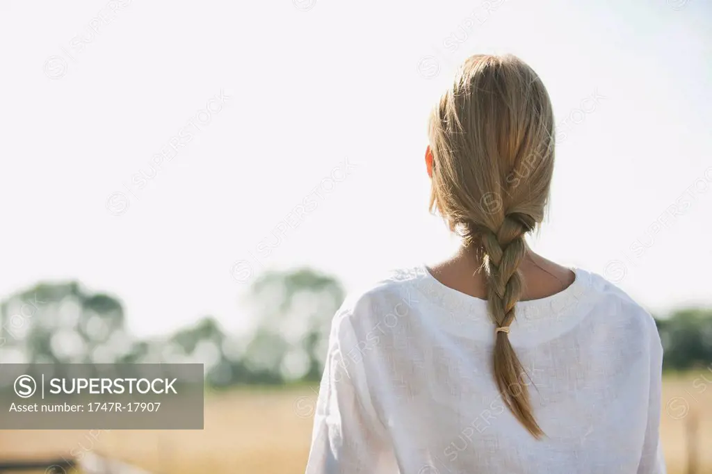 Mid_adult woman looking into distance at field, rear view