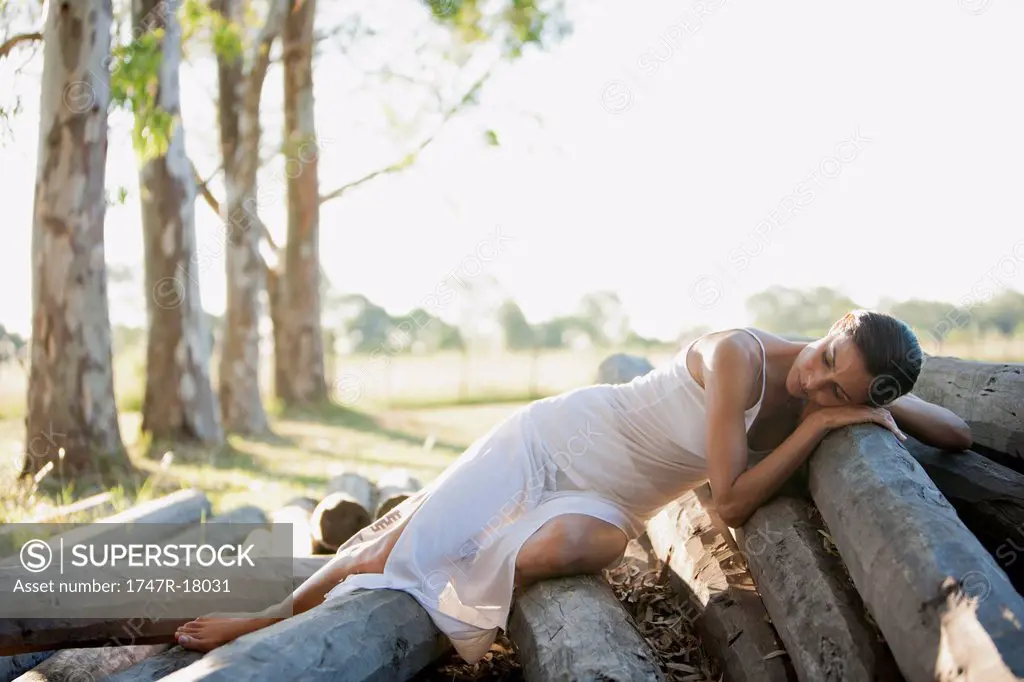 Woman reclining on pile of logs