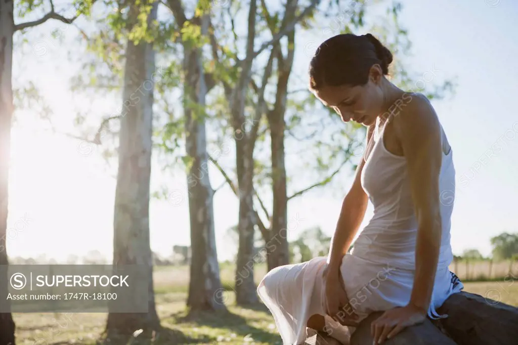 Woman sitting on top of log pile