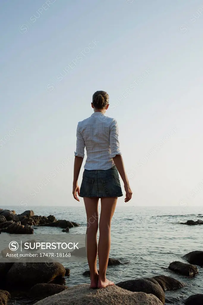 Girl standing on rock looking at ocean