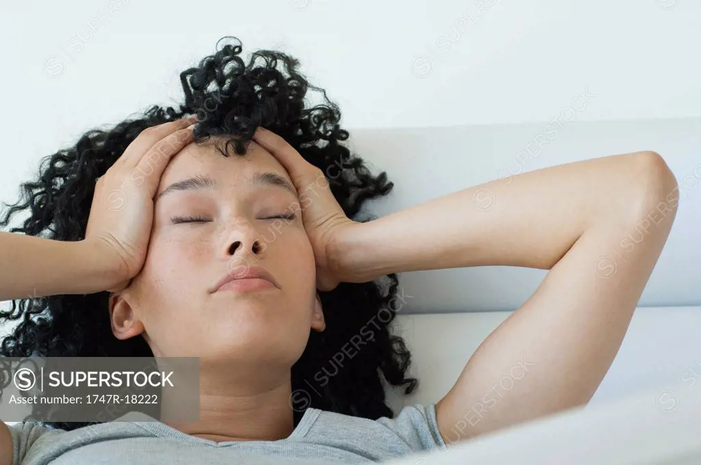 Young woman holding her head, eyes closed