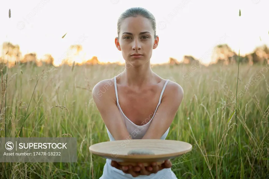 Young woman holding out plate with stone