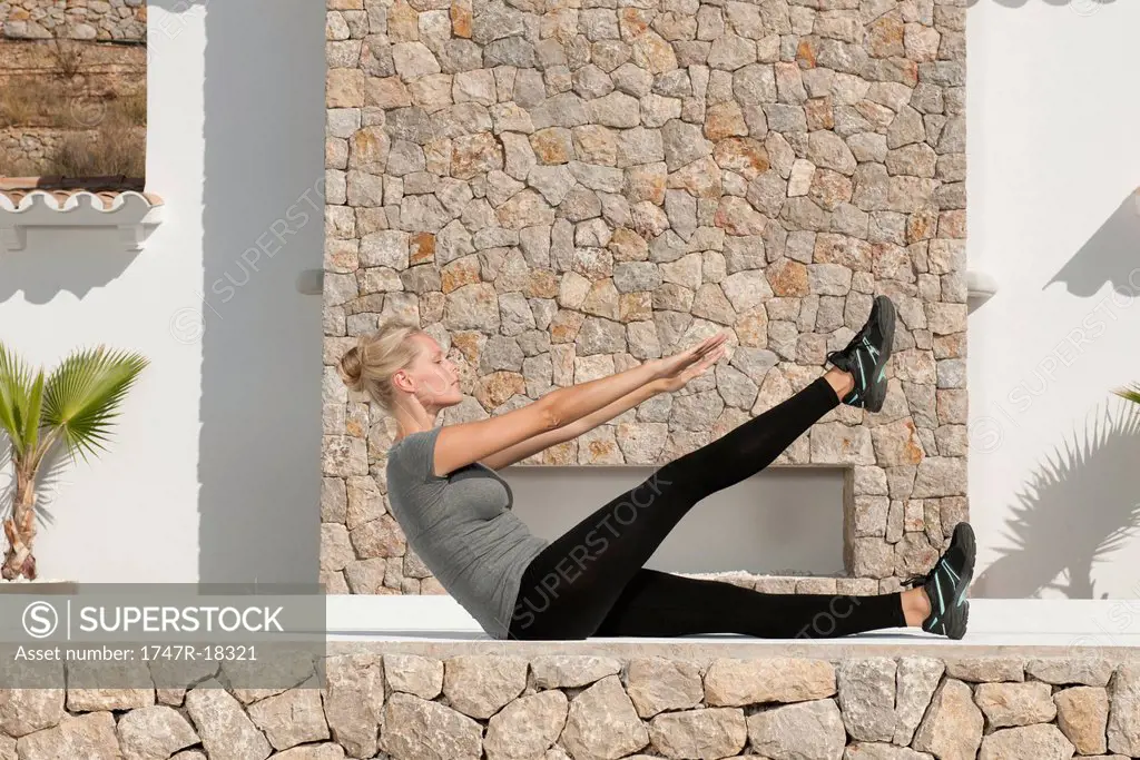 Young woman doing sit_ups outdoors, side view