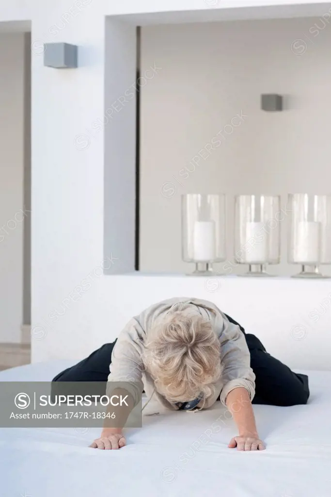 Woman kneeling on bed, leaning forward