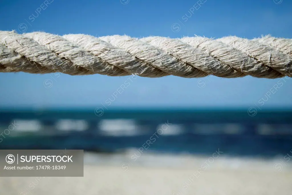 Close_up of weathered rope with beach in background
