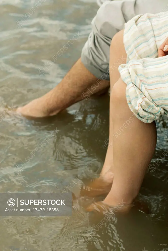 Couple soaking feet in water, cropped