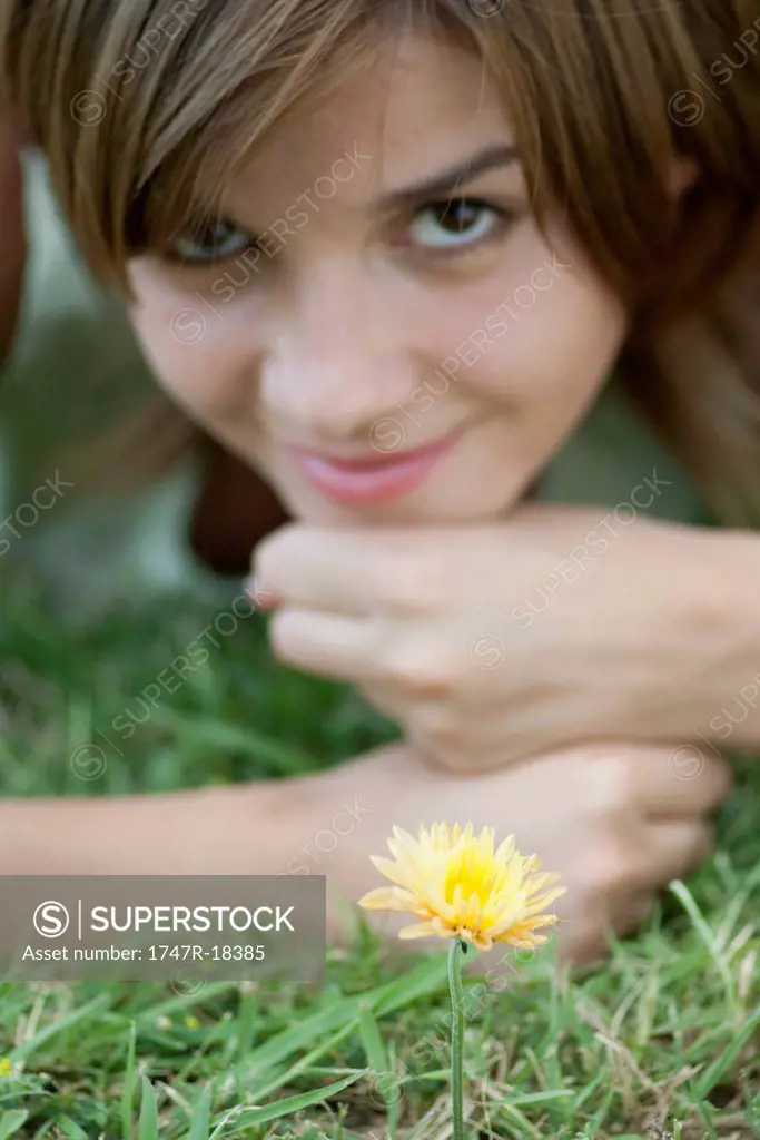 Young woman lying in grass by yelllolw flower