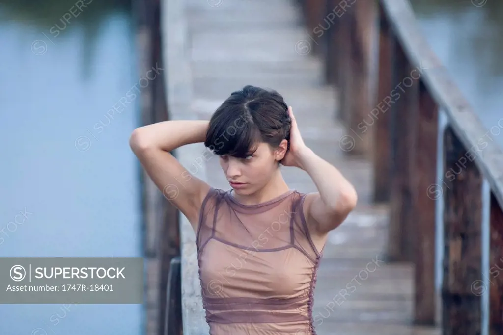 Young woman walking on dock with hands in hair