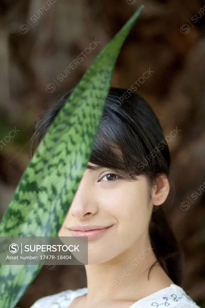 Young woman behind snake plant leaf