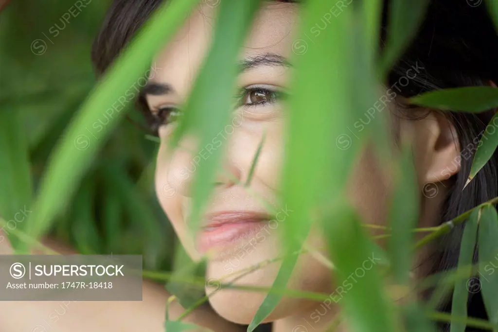 Young woman behind foliage, portrait