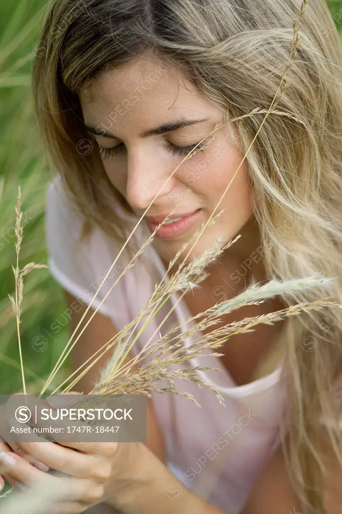 Young woman holding grass with eyes closed