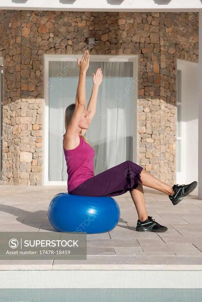 Young woman doing exercise on fitness ball